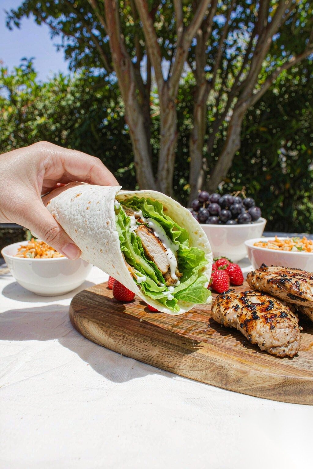 Grilled Chicken Power Wrap held in hand outdoors at a casual healthy lunch setting