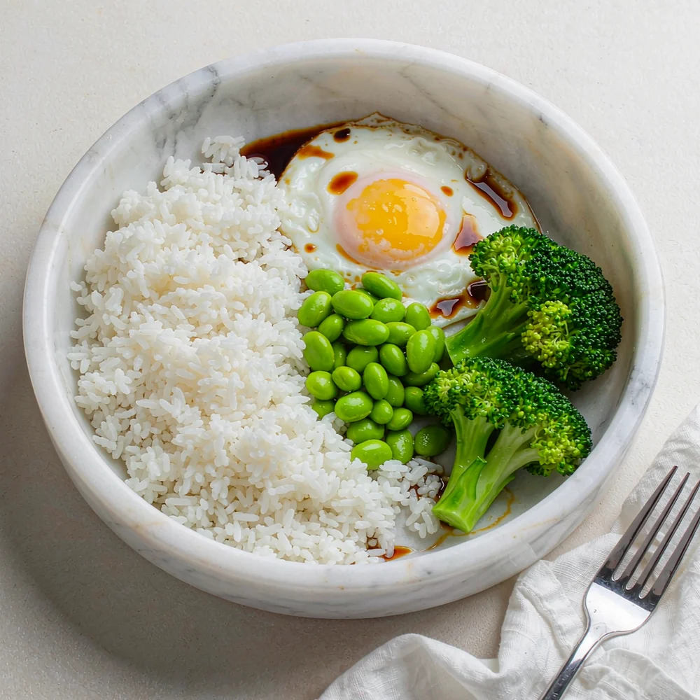 Microwave egg and edamame rice bowl — rice, soft egg, edamame and broccoli in a shallow bowl