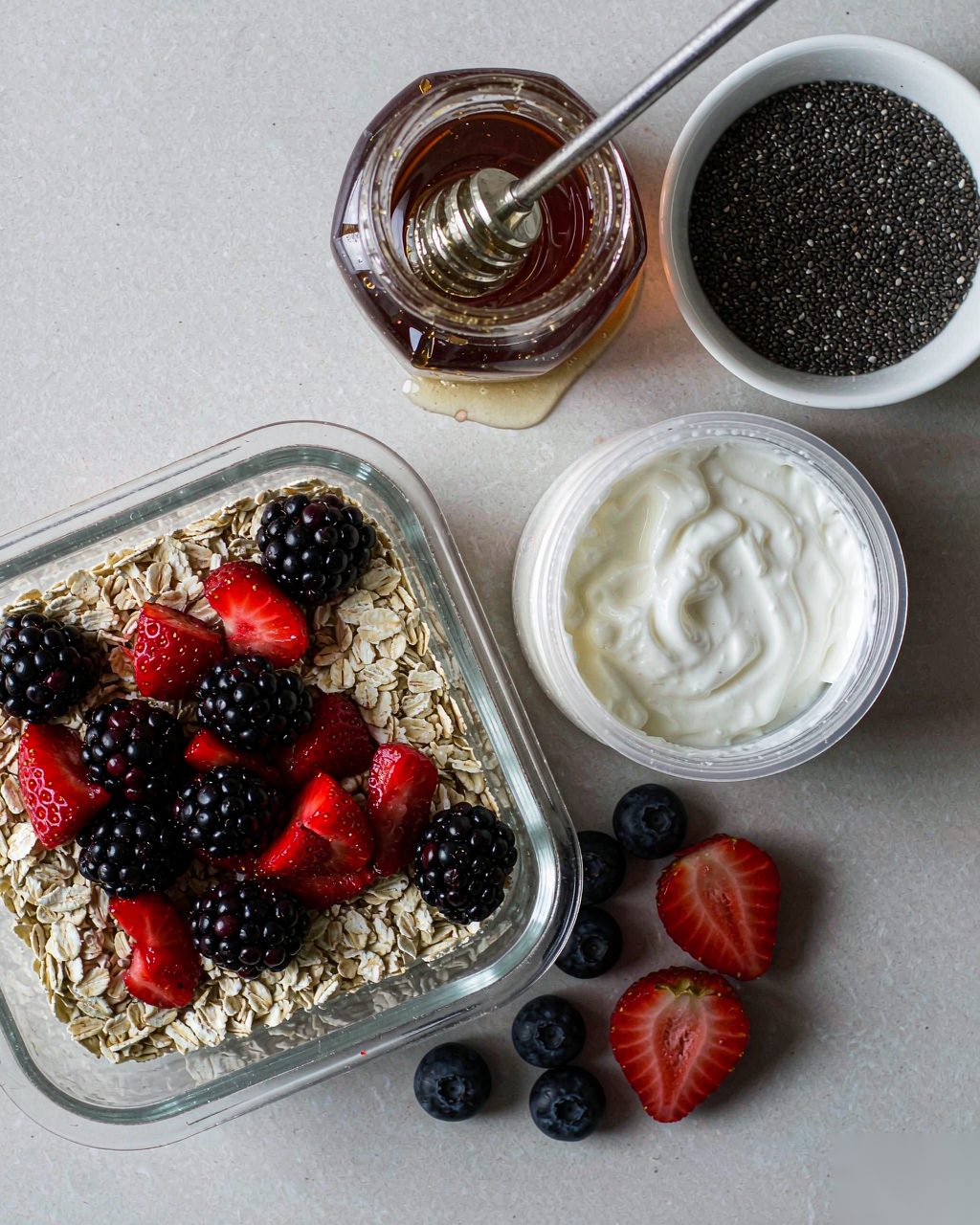 Flat lay of fresh overnight oats ingredients: oats, yogurt, berries, chia, honey
