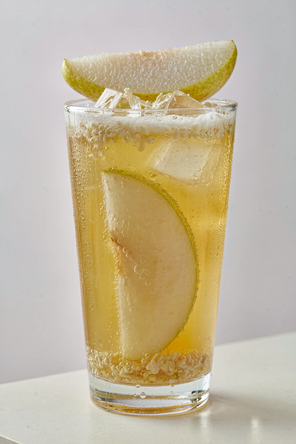 Osmanthus and Pear Sparkling Wellness Drink — sugar-free sparkling herbal drink with poached snow pear and osmanthus flowers in a tall glass with fine bubbles