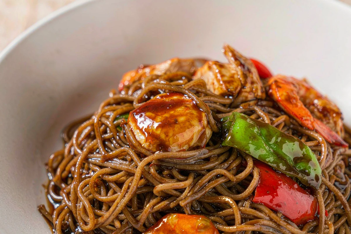 Soba close-up — sauce-drizzled noodles with egg, shrimp and chicken