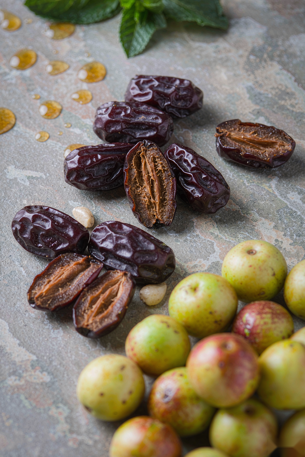 Fresh prunes and emblic myrobalan fruits with honey on stone